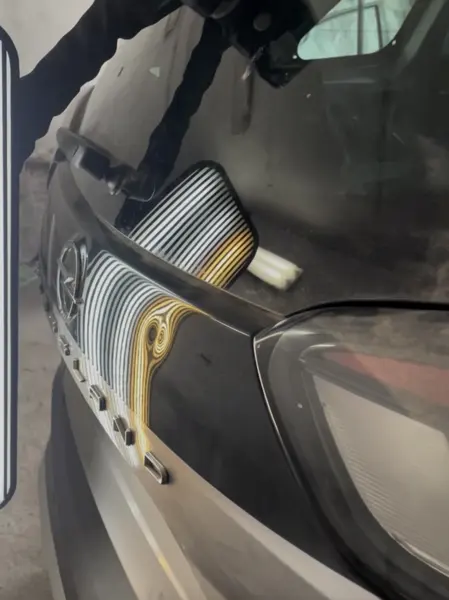 Wgniecenie na klapie bagażnika obok tylnej lampy, żółte pasy lampy zawijają się w okręgi - wgniotki do wyciągnięcia metodą PDR